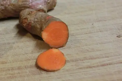 Fresh turmeric rhizome cut to show its orange interior